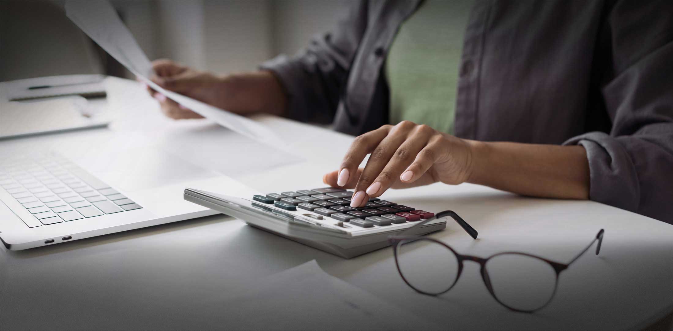 Woman accountant using calculator and computer in office panoramic banner, finance and accounting concept